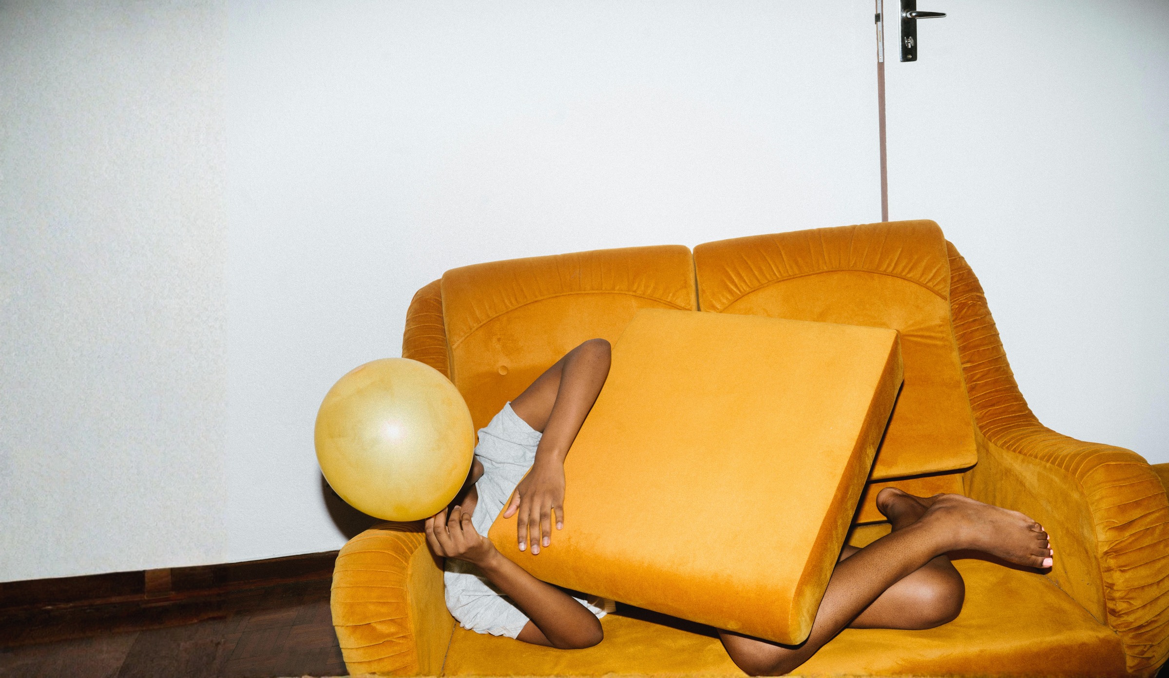 Person relaxing on mustard velvet sofa